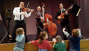 Trio de musiciens avec des enfants lors d'un spectacle.